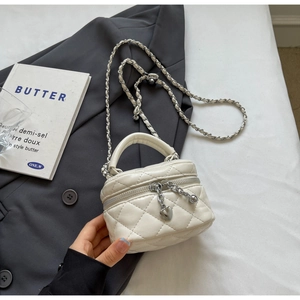 Detail of white quilted mini box bag with heart charm and silver metal chain strap