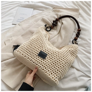 Détail du sac cabas au crochet beige avec des perles en bois sur la bandoulière