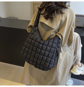 Detail of black quilted puffer bag showing large diamond stitch pattern and nylon texture