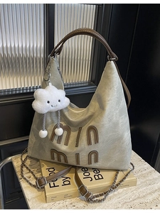 Grey canvas tote bag with brown leather patch and plush charm on marble background