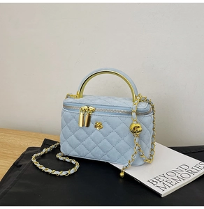 Detailed view of light blue quilted leather bag with gold handle and floral clasp