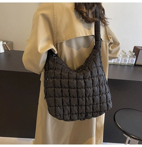 Close-up of black quilted cloud bag with puffy nylon texture on a casual trench coat