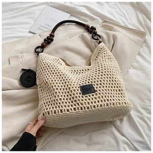 Détail d'un sac cabas en crochet blanc cassé avec des poignées en perles de bois marron foncé