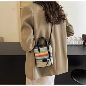 Detail of colorful striped woven bucket bag with leather handles and a shoulder strap