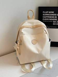 Minimalist cream white nylon commuter backpack for women on a marble tabletop