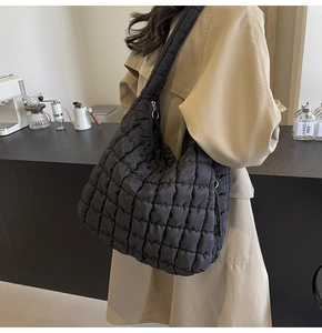 Detail of black quilted cloud bag with glossy puff texture and thick shoulder strap
