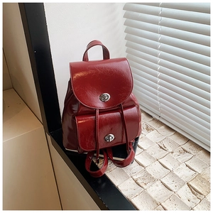 Detail of red patent leather mini backpack featuring silver metallic twist lock and texture