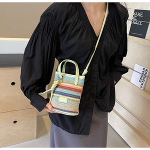 Detail of colorful striped woven mini bag with green handles and side spiral charm