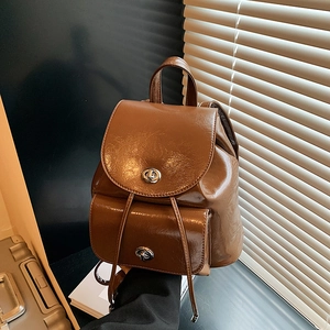 Close-up of vintage brown leather backpack with silver twist lock and drawstring detail