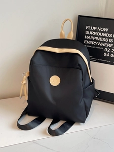 Lightweight black nylon backpack with beige trim on a marble surface, casual style