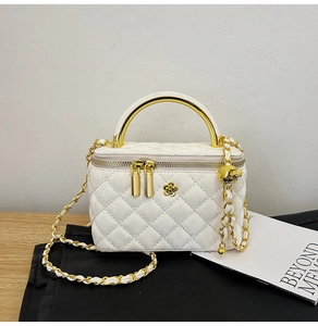Detailed macro view of white quilted leather bag with golden camellia hardware and chain