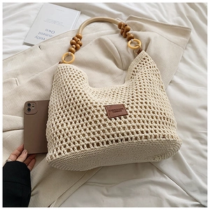 Gros plan d'un sac cabas en paille tissée avec texture au crochet et poignée en perles