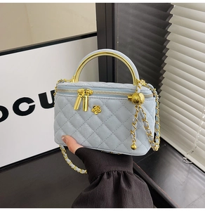 Detail of light blue quilted mini vanity bag with gold handle and chain strap
