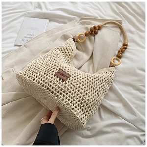 Vue détaillée du sac cabas en maille crème avec poignées en perles de bois et anneaux sombres