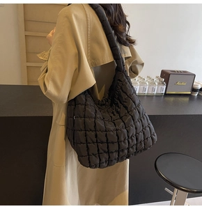 Detail of black quilted cloud bag showing fluffy nylon texture and large shoulder strap