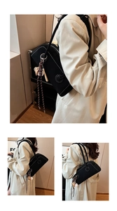 Detail of black underarm bag with white contrast stitching and baseball pendant