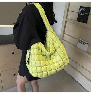 Macro detail of large neon yellow quilted tote bag with square puff stitching on a model