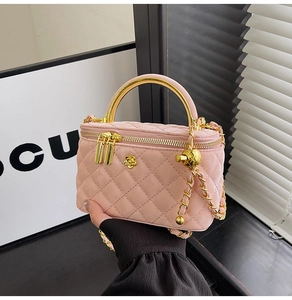 Detail of pink quilted vanity bag with gold handle and chain strap on light background