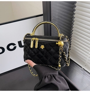 Close-up of quilted black velvet vanity bag with gold handle and metal flower detail