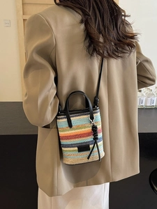 Bohemian striped woven straw crossbody bag with black leather handles and long shoulder strap
