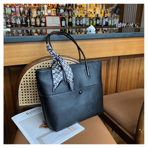 Close-up of black lychee grain leather tote bag with a geometric heart pattern silk scarf