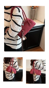 Detail view of burgundy suede underarm bag featuring decorative charms and embossed logo