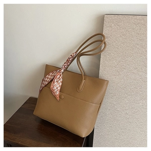 Close-up of brown litchi pattern tote bag with decorative silk scarf and front pocket