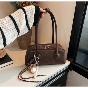 Detailed macro view of brown suede shoulder bag with debossed lettering and baseball charms