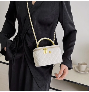 Detail of white quilted leather chain bag featuring gold handles on a model