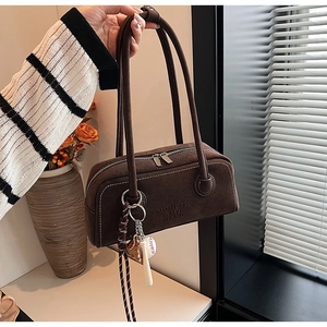 Detail view of brown suede underarm bag with MUHETI SHI SHANG text and baseball charm