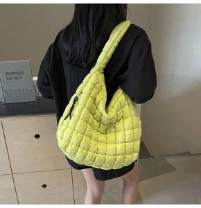 Detailed back view of a large fluorescent yellow quilted cloud bag on a female model