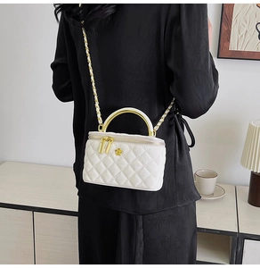 Rear view of white quilted vanity bag with golden chain strap on a female model