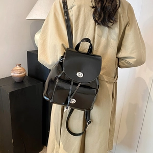 Rear view of high-shine black leather backpack featuring adjustable straps and silver lock