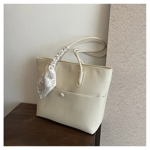 Detail of beige faux leather tote bag with lychee texture and heart print silk scarf