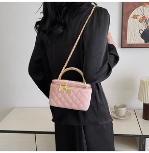 Detail of pink quilted chain bag featuring a golden camellia logo and top handle
