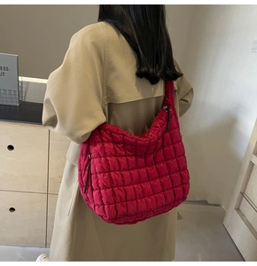 Detail of quilted puffy hobo bag in bright red showing soft nylon texture and wide strap