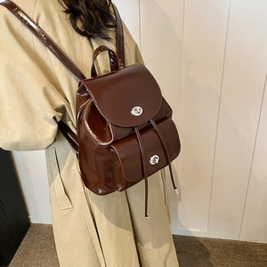 Detail of dark brown glossy leather backpack with silver twist lock and drawstring closure