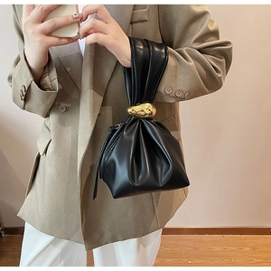 Detail van zwarte geplooide cloud bag met een grote decoratieve gouden metalen kogel