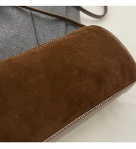 Detail of brown suede shoulder bag featuring premium white contrast stitching texture