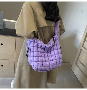 Detail of purple quilted cloud bag with padded waffle texture on a khaki trench coat