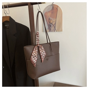 Detail of dark brown leather tote bag with a heart-patterned silk scarf on handle