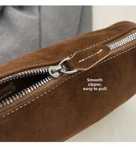 Detail of smooth silver zipper with suede puller and neat white stitching on brown bag
