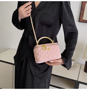 Pink quilted crossbody bag with gold handle and floral clasp shown on a shoulder