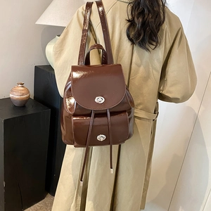 Detail of dark brown glossy leather backpack with silver metal turn-lock and drawstring