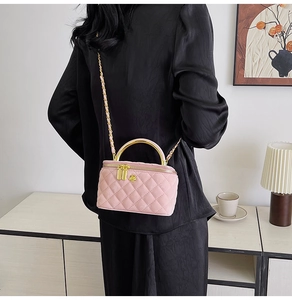 Pink quilted crossbody box bag with gold floral logo shown on a person in a lifestyle setting
