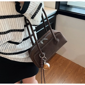 Detail showing dark brown suede underarm bag with white contrast stitching and silver zipper