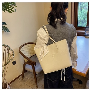 Detailed view of white lychee leather tote bag with functional outer pocket and silk scarf