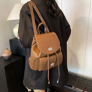 Close-up of brown glossy leather backpack with silver twist lock and drawstring details