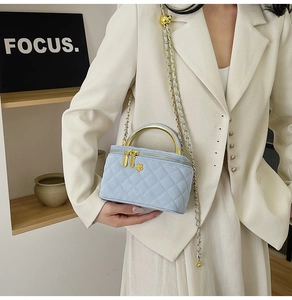 Detailed view of light blue quilted chain bag featuring a gold handle and crossbody strap