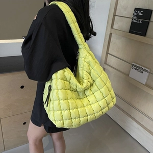 Minimalist lemon green oversized quilted puffer cloud bag worn as a shoulder crossbody bag